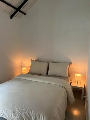 a bedroom with a white bed with two lamps at Un apartamento cálido y céntrico rodeado de jardines in Guatapé