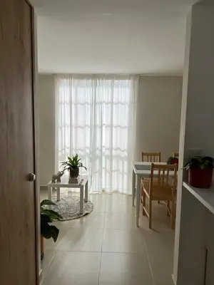 a living room with a table and a window at Un apartamento cálido y céntrico rodeado de jardines in Guatapé
