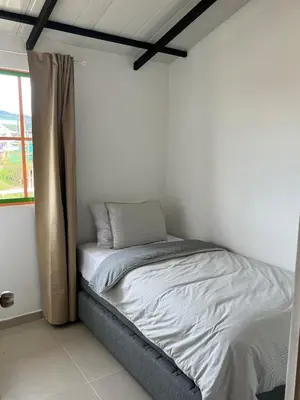 a bed in a white room with a window at Un apartamento cálido y céntrico rodeado de jardines in Guatapé