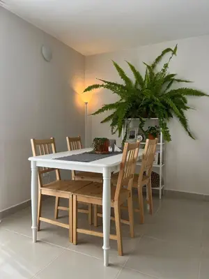 a white dining room table with chairs and a plant at Un apartamento cálido y céntrico rodeado de jardines in Guatapé