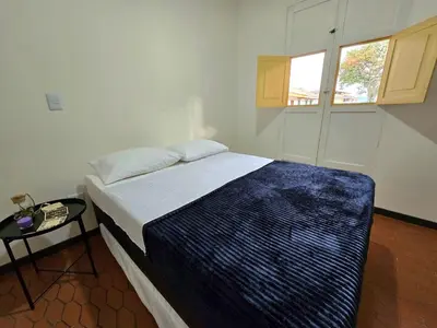 a bedroom with a bed and a table and a window at Rincon del Parque, Jerico - 2 Hab - 2 Cama Tarima - 1 Baño in Jericó