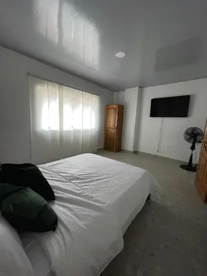 a bedroom with a large white bed and a flat screen tv at Casa Selva in San Carlos