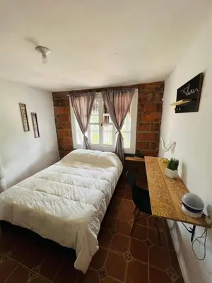 a bedroom with a bed and a wooden table at SELENE Hostal Coworking Café in Medellín
