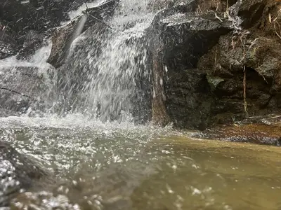 a waterfall on the side of a river at Cabaña Selvática y Manantiales, San Miguel Guarne in Guarne