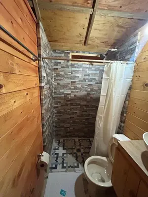 a bathroom with a toilet and a brick wall at Cabaña Selvática y Manantiales, San Miguel Guarne in Guarne