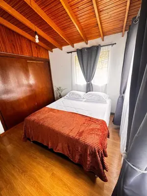 a bedroom with a large bed with a wooden floor at Hostal Galería de la Montaña, Medellin in Estación El Salto