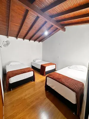 two beds in a room with wooden floors at Hostal Galería de la Montaña, Medellin in Estación El Salto
