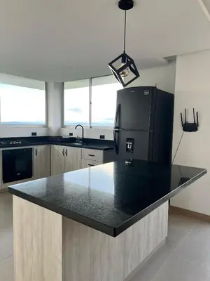 a kitchen with a black counter top and a refrigerator at Finca Doña Eva in Manizales
