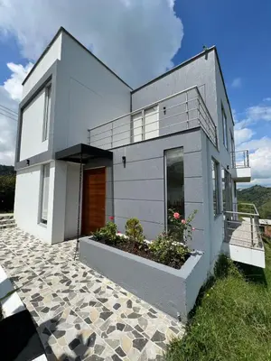 a white house with a porch and some plants at Finca Doña Eva in Manizales