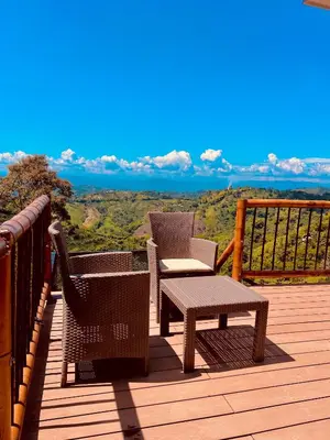 a wooden deck with two chairs and a table at Glamping La Nonita tipo cabaña Luxury in Manizales