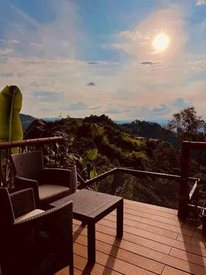 a balcony with a chair and a table and the sun at Glamping La Nonita tipo cabaña Luxury in Manizales