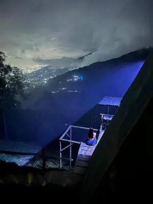 a person sitting on a platform overlooking a valley at night at Chalet Guadalupe - Girardota