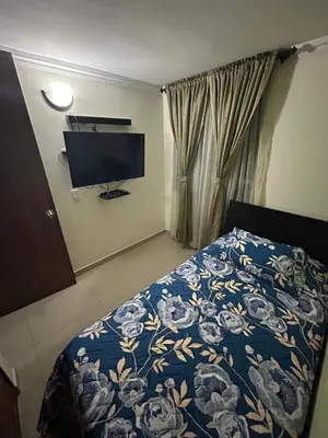a bedroom with a bed with a blue comforter and a television at Apartment in Bello in Medellín