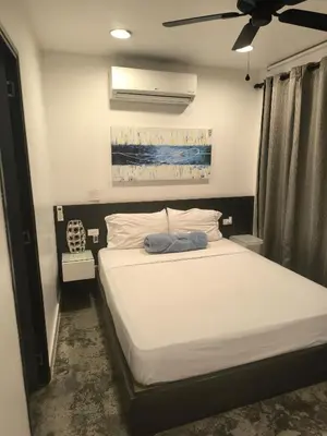 a bedroom with a bed with white sheets and a ceiling fan at Poblado Luxury Suites in Medellín
