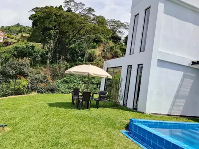 a table and chairs under an umbrella next to a swimming pool at Finca privada Villa Antonia