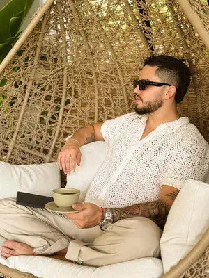 a man sitting in a chair with a cup of coffee at Ivanna Hotel Campestre - Santa Fe de Antioquia in Santa Fe de Antioquia