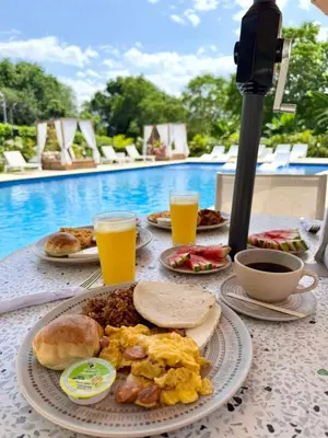 a table with a plate of breakfast food next to a pool at Ivanna Hotel Campestre - Santa Fe de Antioquia in Santa Fe de Antioquia