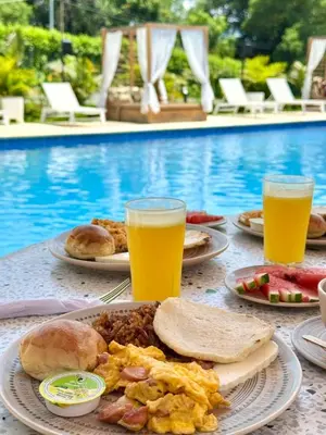 a table with plates of food and two glasses of orange juice at Ivanna Hotel Campestre - Santa Fe de Antioquia in Santa Fe de Antioquia