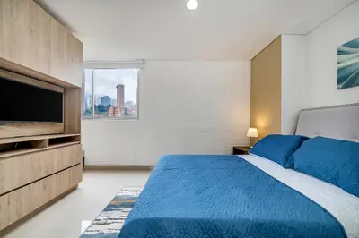 a bedroom with a bed and a flat screen tv at Apartamentos Oslo Tesoro by HOUSY in Medellín