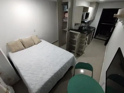 a small bedroom with a bed and a kitchen at Apartaestudio Ofisuite-Medellin in Medellín