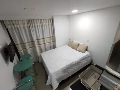 a small bedroom with a bed and a table and chairs at Apartaestudio Ofisuite-Medellin in Medellín