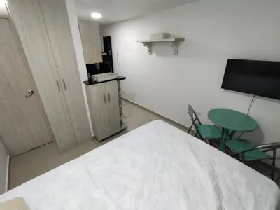 a room with a bed and a table and a tv at Apartaestudio Ofisuite-Medellin in Medellín