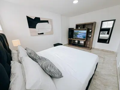 a bedroom with a white bed and a tv at Casa Lujosa vacacional El Poblado Medellín Por día Con Piscina Jacuzzi AC 9br in Estación El Salto