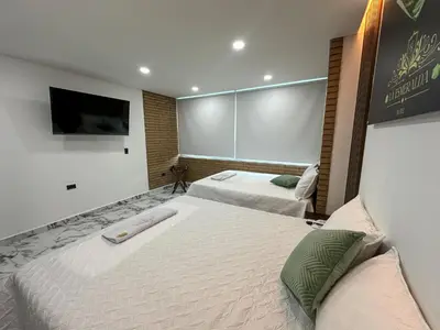 a bedroom with two beds and a flat screen tv at Hotel La Esmeralda Doradal in Doradal
