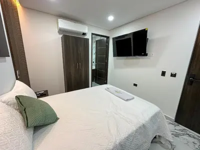 a bedroom with a bed with a tv on the wall at Hotel La Esmeralda Doradal in Doradal