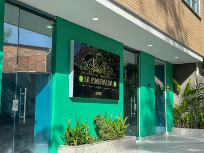 a green building with a sign on the side of it at Hotel La Esmeralda Doradal in Doradal