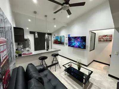 a living room with a black couch and a kitchen at London suites, By Poblado Suites in Medellín