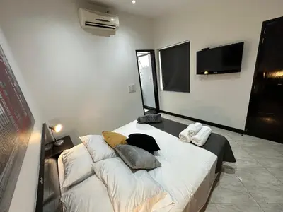 a bedroom with a bed with pillows and a tv at London suites, By Poblado Suites in Medellín