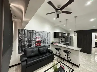 a living room with a ceiling fan and a kitchen at London suites, By Poblado Suites in Medellín