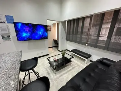 a living room with a couch and a tv on the wall at London suites, By Poblado Suites in Medellín