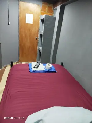 a bedroom with a bed with a red blanket and a door at Dulce Hogar Aparta Hotel in Medellín