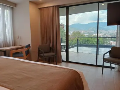a hotel room with a bed and a balcony with a view at Hotel Rulay Medellin in Medellín
