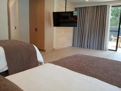 a hotel room with two beds and a flat screen tv at Hotel Rulay Medellin in Medellín
