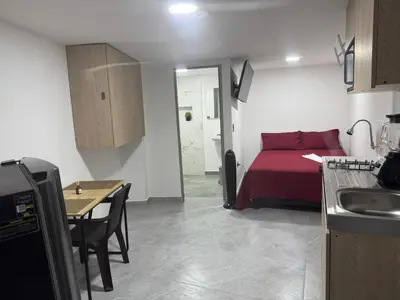 a room with a bed and a table and a kitchen at Villa Loreto Aparta estudio 204 in Medellín