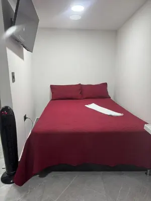 a bedroom with a red bed with a red blanket at Villa Loreto Aparta estudio 204 in Medellín