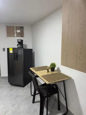a kitchen with a table and a refrigerator at Villa Loreto Aparta estudio 204 in Medellín