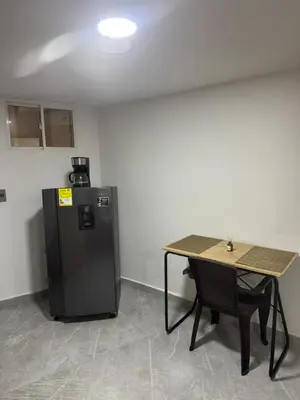 a room with a table and a small refrigerator at Villa Loreto Aparta estudio 204 in Medellín