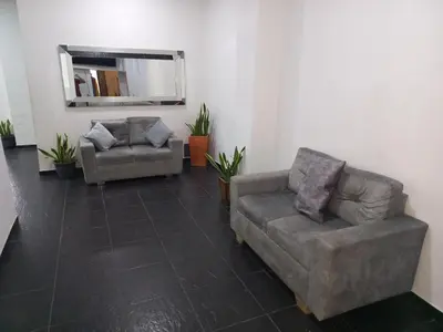 a living room with two couches and a mirror at Hotel Centrica Del Palo 45 in Medellín