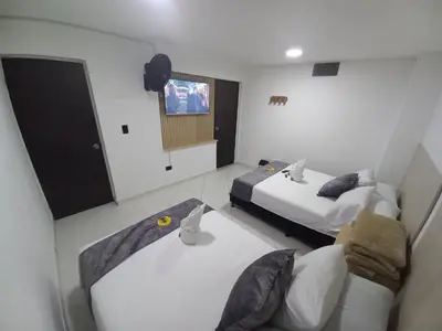 a hotel room with two beds and a tv at Hotel Centrica Del Palo 45 in Medellín
