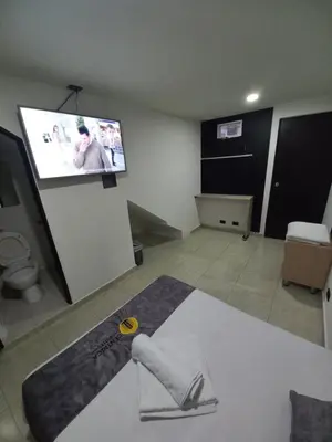a living room with a flat screen tv on the wall at Hotel Centrica Del Palo 45 in Medellín