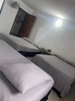 a room with two beds and a light on the wall at Hmetrohotel in Medellín