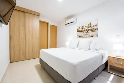 a bedroom with a white bed and a wooden cabinet at Apartamento San Jerónimo - Antioquia in San Jerónimo