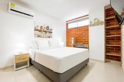 a bedroom with a white bed and a brick wall at Apartamento San Jerónimo - Antioquia in San Jerónimo