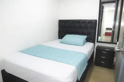 a small bedroom with a bed with a blue pillow at El ensueño in Manizales