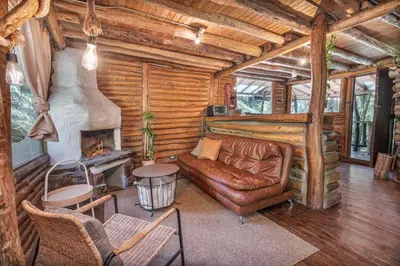 a living room with a couch and a fireplace in a log cabin at Cabañas Casa Monte en Santa elena in Medellín