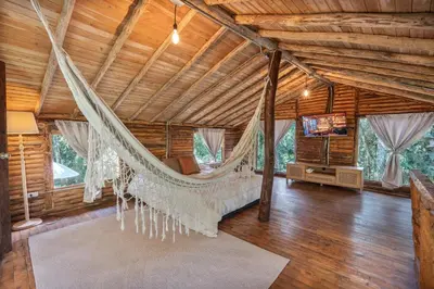 a room with a hammock in a log cabin at Cabañas Casa Monte en Santa elena in Medellín